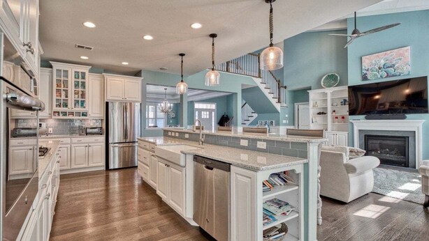 A spacious kitchen with white cabinetry, a central island, and a fireplace.