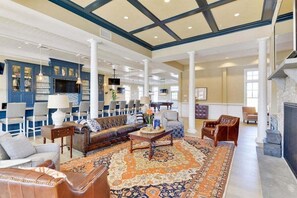 A spacious lobby with a large seating area, a fireplace, and a bar with blue cabinets.