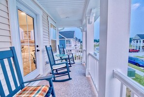 A covered porch with rocking chairs and a glass door.