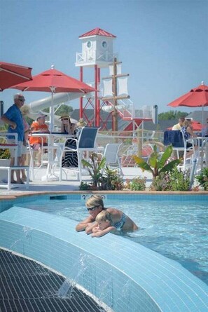 Une piscine dotée d’un poste de surveillance pour les sauveteurs, de chaises longues et de parasols.