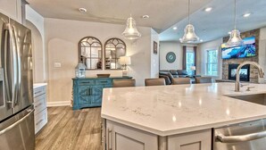 A modern kitchen with a marble island, stainless steel appliances, and a dining area with a TV.