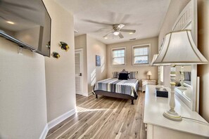 A bedroom with a bed, a ceiling fan, a dresser, and a mirror.