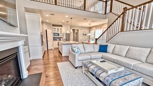 A spacious living area with a fireplace, a sofa, a coffee table, and a staircase.