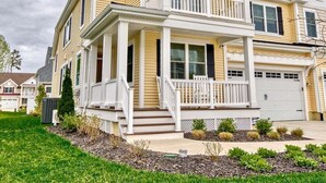 A two-story residential house with a front porch, a garage, and a well-maintained lawn.