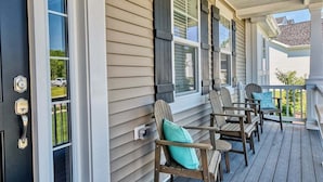 A porch with wooden chairs and a door.