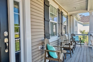 A porch with wooden chairs and a door.