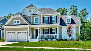 A two-story house with a front porch, a garage, and a well-maintained lawn.