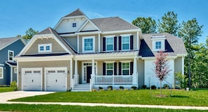 A two-story house with a front porch, a garage, and a well-maintained lawn.