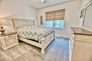A bedroom with a bed, nightstand, dresser, window with blinds, and a wall-mounted artwork. - Coastal Club * 4BR Lewes Beach Home (Lewes)