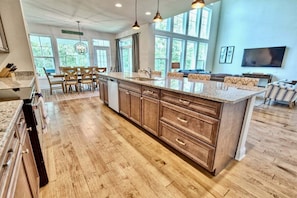 A spacious kitchen with wooden cabinets, a granite countertop, and a dining area with chairs. - Coastal Club * 4BR Lewes Beach Home (Lewes)
