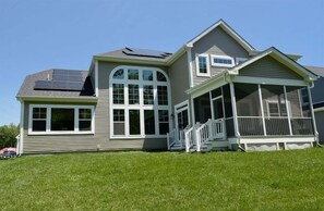 A two-story house with a large front porch, a covered area, and solar panels on the roof. - Coastal Club * 4BR Lewes Beach Home (Lewes)