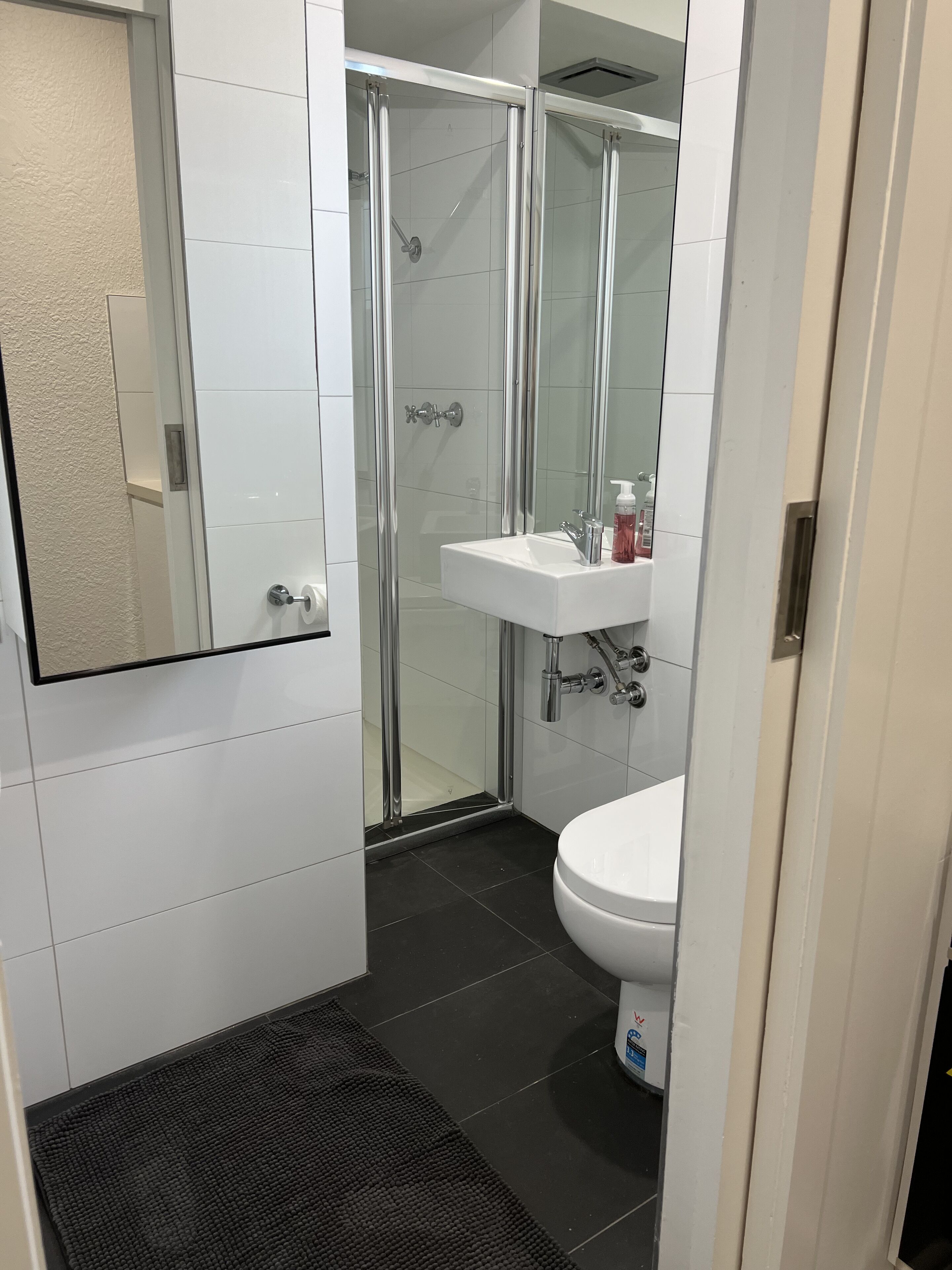 A modern bathroom with a glass-enclosed shower, a white sink, and a toilet.