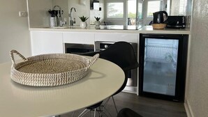 Une cuisine compacte équipée d’un réfrigérateur, d’un évier et d’un coin repas avec une table ronde et des chaises.