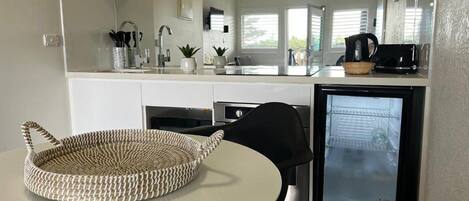 A compact kitchen with a refrigerator, a sink, and a dining area with a round table and chairs.