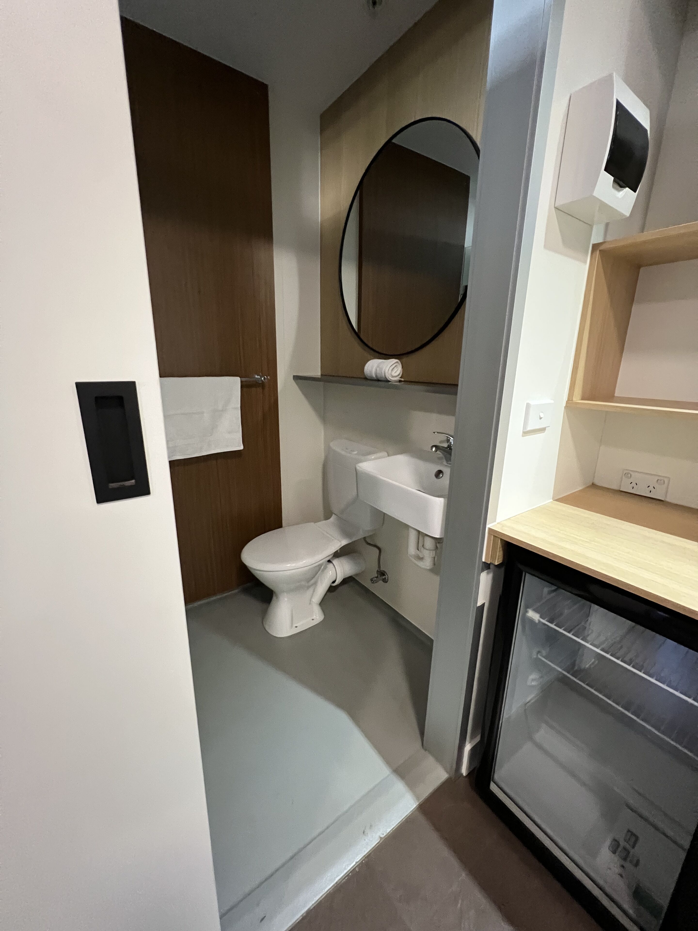 A compact bathroom with a toilet, sink, and mirror.