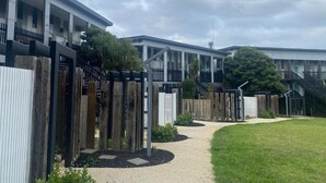 Un bâtiment moderne doté d’une allée couverte, de clôtures en bois et d’une zone herbeuse.