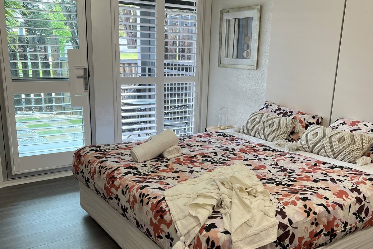 A bedroom with a bed, a door, and a view of the outside.
