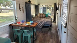 A compact bedroom with a bed, a small table, and chairs. There is a window providing a view of the outdoors. - Dog friendly! - #11 is 1 of 3 containers now dog friendly! (Blanco County)