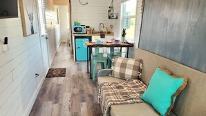 A compact living space with a kitchenette, a dining area, and a sofa with a plaid blanket and turquoise pillow. - Dog friendly! - #11 is 1 of 3 containers now dog friendly! (Blanco County)