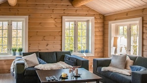 A cozy log cabin interior with two sofas, a coffee table, and large windows offering views of trees. - 3 bedroom nice home in Oppdal (Oppdal)