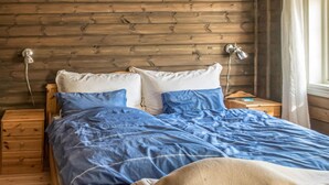 A bed with a blue and white duvet, wooden headboard, and bedside lamps. - 3 bedroom nice home in Oppdal (Oppdal)