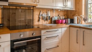 A kitchen with wooden cabinets, a stainless steel oven, and a window with a view of trees. - 3 bedroom nice home in Oppdal (Oppdal)
