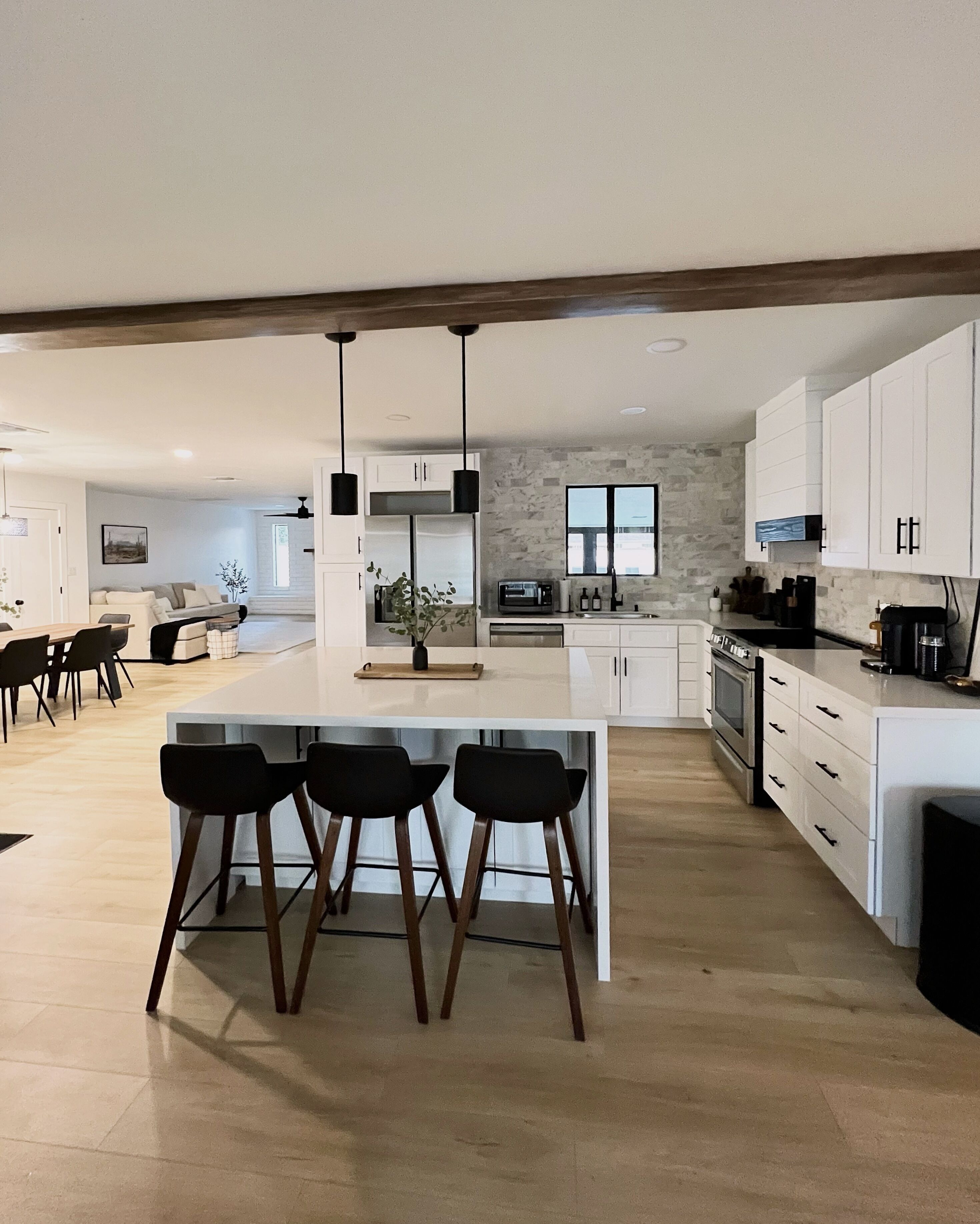 A modern kitchen with a central island, bar stools, and a dining area with a table and chairs.