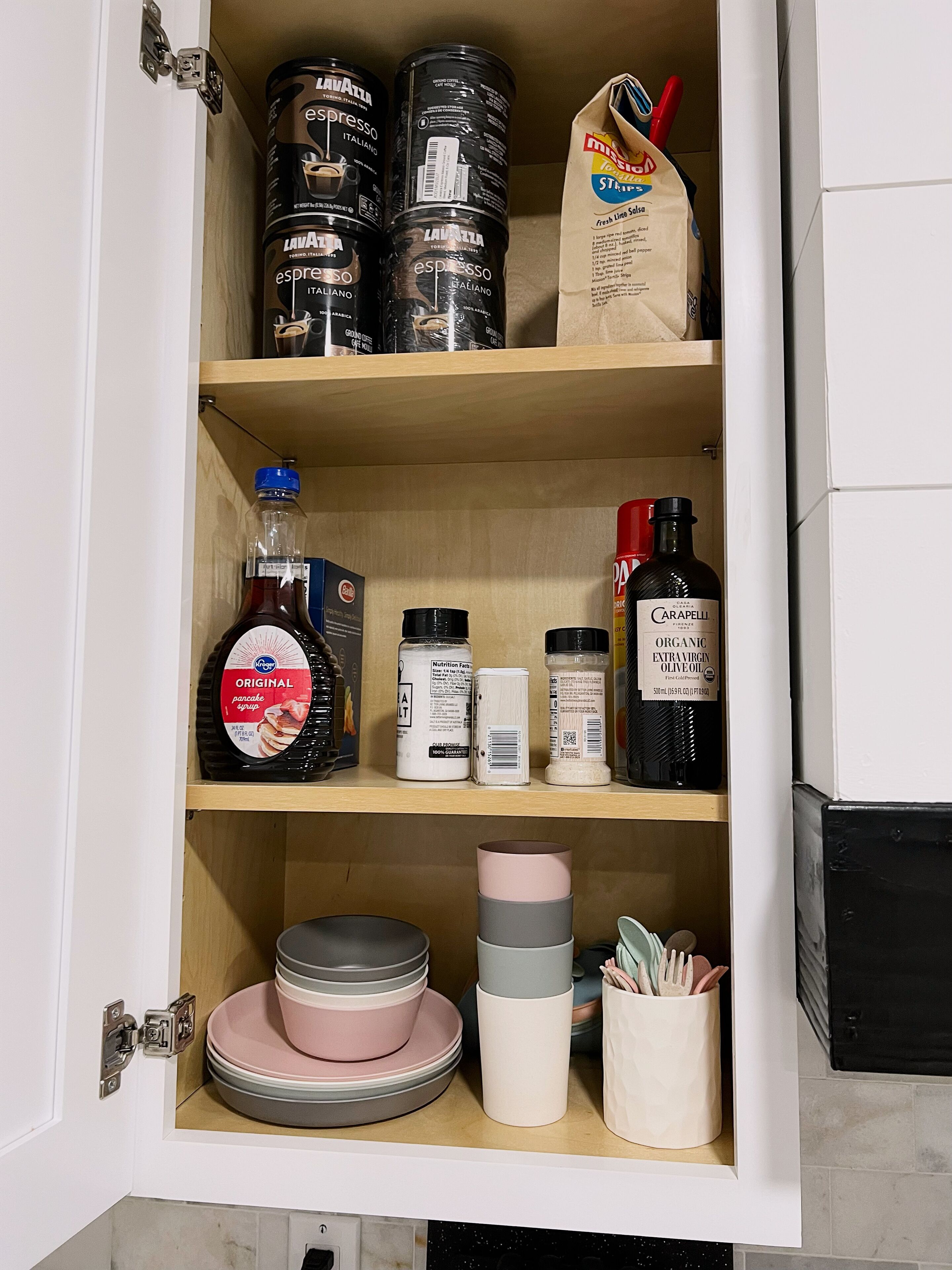A kitchen cabinet with various food items and kitchenware.