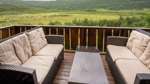 A deck with wicker furniture and a view of a green valley. - Awesome home in Hemsedal with WiFi (Hemsedal)