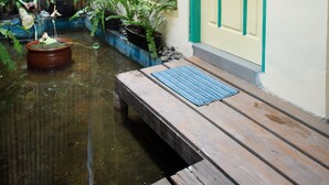 A narrow courtyard with a wooden bench, potted plants, and a statue. - Rumah Kalpataru (Yogyakarta)
