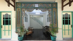 A building entrance with a staircase leading inside, flanked by two doors and two potted plants. - Rumah Kalpataru (Yogyakarta)
