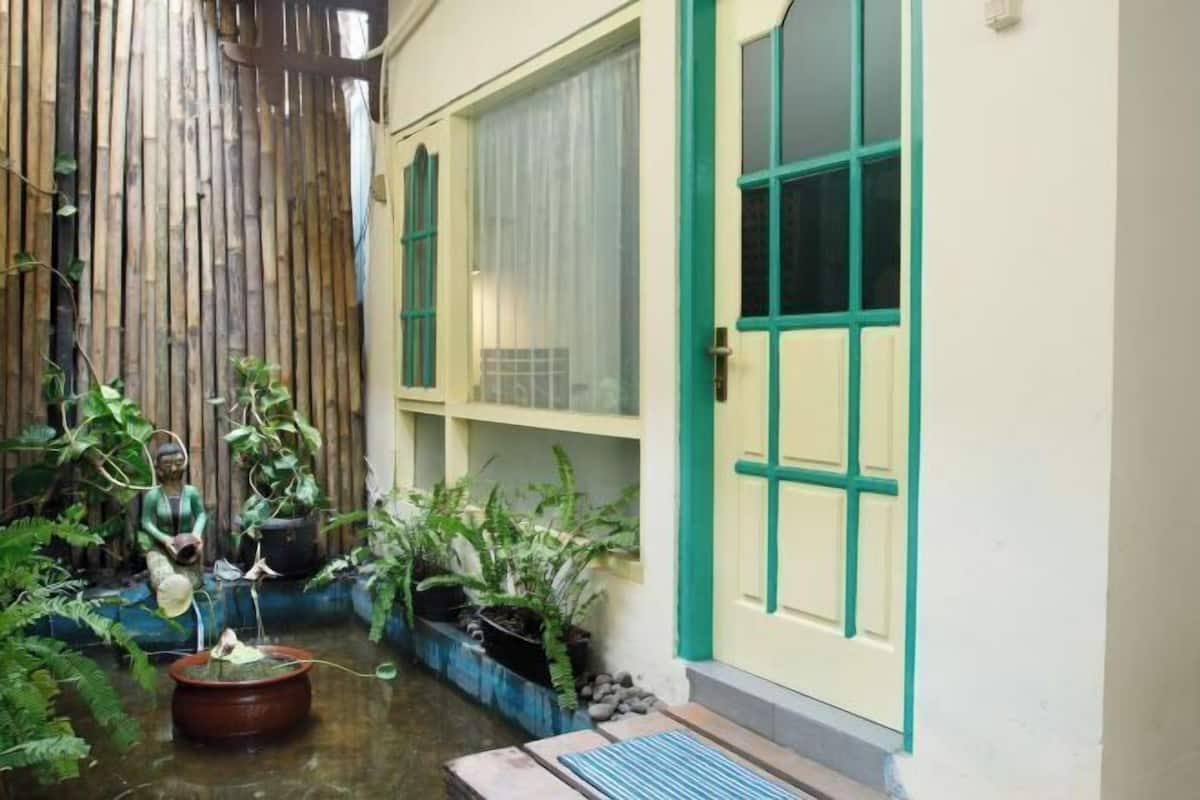 Une petite cour agrémentée d’un élément décoratif avec de l’eau, de plantes en pot et d’une statue.