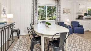 Een eetgedeelte met een ronde tafel, zwarte stoelen en een kamerkleed met een patroon.