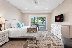 A bedroom with a bed, a dresser, a TV, and a view of the outdoors. - 🌆 539 Bay St Lakeview Condo | Walk to Downtown & Beach ➠ 102W (Traverse City)