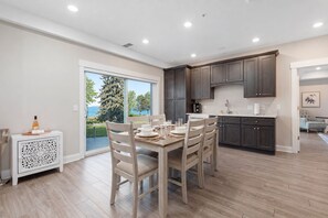 Une cuisine moderne avec des meubles de couleur sombre, une table à manger dressée pour quatre personnes et une vue sur l’extérieur.
