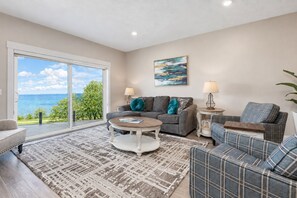 A living room with a large window, a sofa, a coffee table, and a patterned rug.