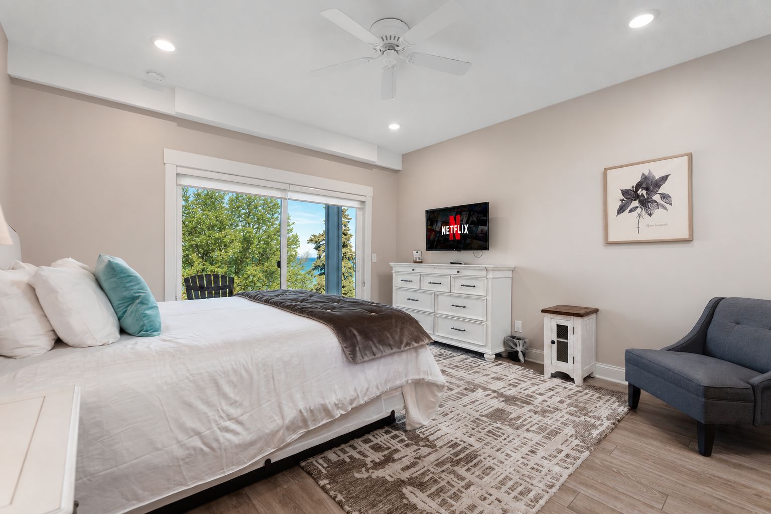 A bedroom with a bed, a dresser, a TV, and a chair.