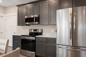 A kitchen with stainless steel appliances, dark cabinets, and a white countertop. - 539 Bay St Lakeview Condo | 204E - Waterfront & Free Parking  204E (Traverse City)