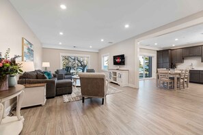 A spacious living area with a sofa, armchairs, a coffee table, and a TV mounted on the wall. - 539 Bay St Lakeview Condo | 204E - Waterfront & Free Parking  204E (Traverse City)