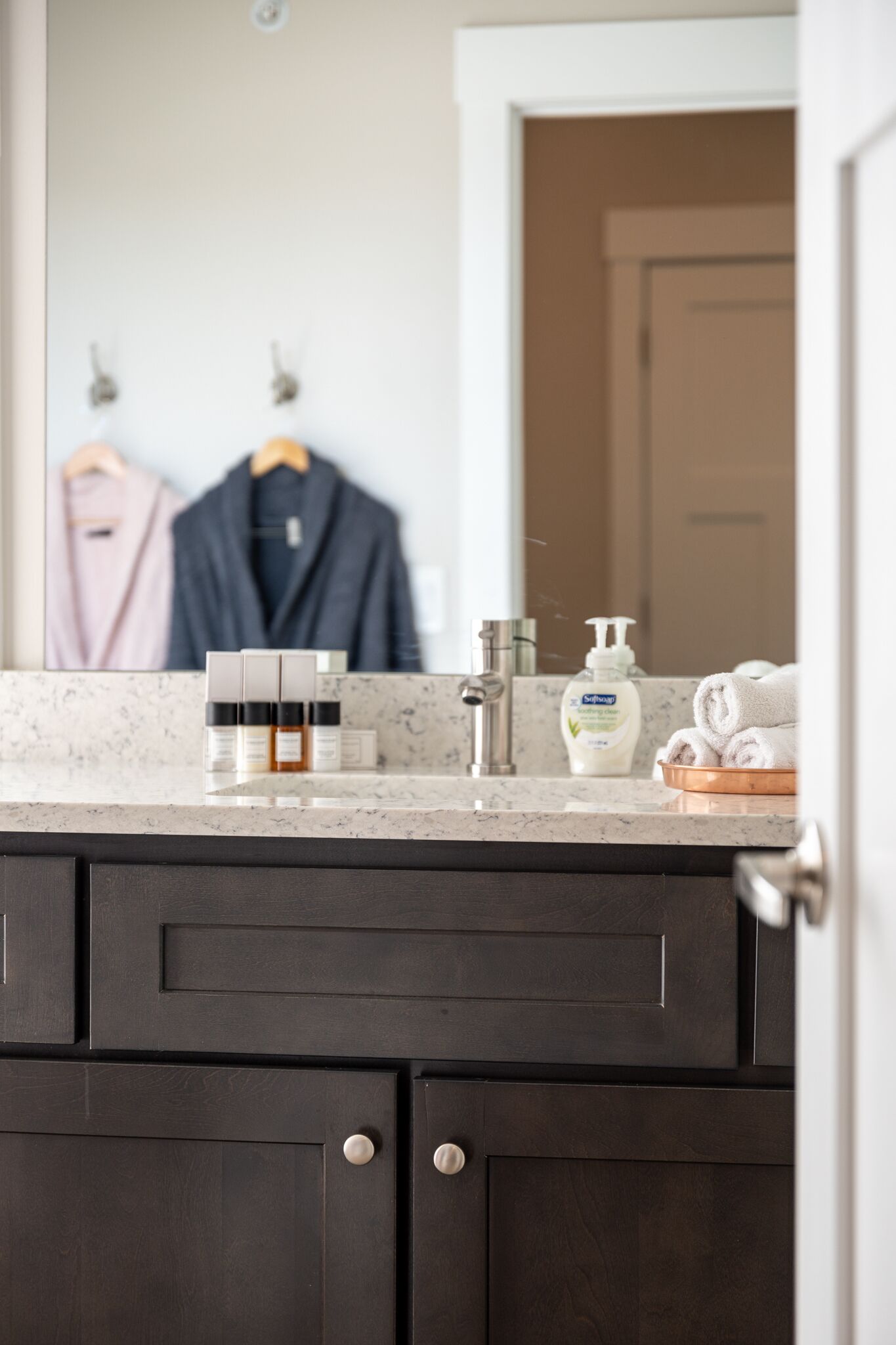 Une salle de bain avec un comptoir en marbre, des meubles en bois foncé, un miroir et des articles de toilette.
