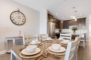 White bowls and woven placemats on a dining table with the kitchen island behind it. - 🌆 539 Bay St Downtown Lakeview Condo | 304E - Waterfront, Free Parking, Moments from festival grounds (Traverse City)