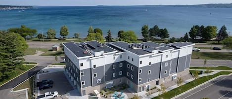 Een meerlaags gebouw met een parkeerplaats, een zwembad en uitzicht op het water.