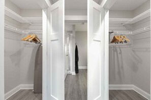 Un couloir avec une armoire en bois, un porte-manteau et une robe noire accrochée au mur.