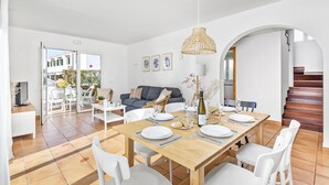 Een eetruimte met een houten tafel gedekt voor vier personen, witte stoelen en een hangende lamp.