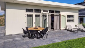 A modern house with a patio, a dining table with chairs, and a small garden area. - 3 bedroom lovely home in Den Oever (Den Oever)