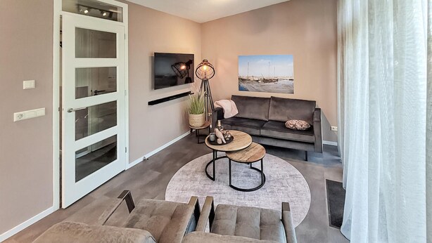 A modern living room with a sofa, a coffee table, and a TV mounted on the wall. - 3 bedroom lovely home in Den Oever (Den Oever)