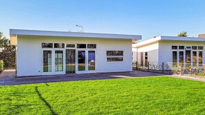 A modern two-story house with a flat roof, large glass windows, and a well-maintained lawn. - 3 bedroom lovely home in Den Oever (Den Oever)