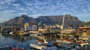 A marina with boats docked, a cityscape with buildings, and a mountain in the background. - Plush Loft Apartment With Signal Hill View (Cape Town)