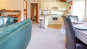 Une cuisine compacte équipée d’un four à micro-ondes, d’un four et d’un évier. On y trouve un coin repas avec une table et des chaises, ainsi qu’un coin salon avec un canapé.