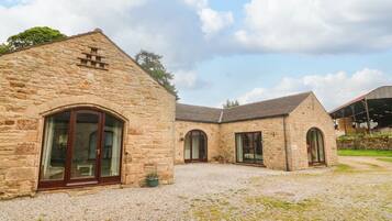 A stone building with arched windows and a gravel driveway.